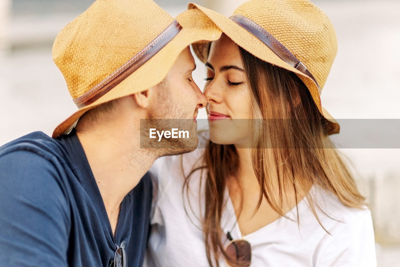adult, two people, hat, women, togetherness, young adult, positive emotion, emotion, love, men, happiness, portrait, headshot, clothing, summer, romance, smiling, casual clothing, lifestyles, sun hat, bonding, relaxation, leisure activity, enjoyment, kissing, vacation, female, person, cheerful, friendship, affectionate, trip, cap, nature, straw hat, holiday, travel, outdoors, fun, long hair, fashion, carefree, embracing, city, travel destinations, photo shoot, day, tourism, beard, water, sunlight, beach