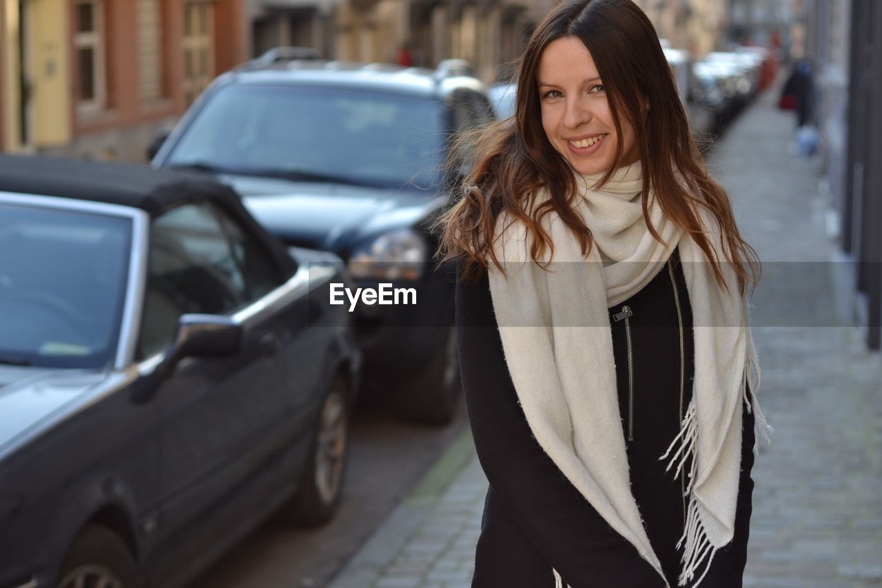 Portrait of smiling woman standing on sidewalk