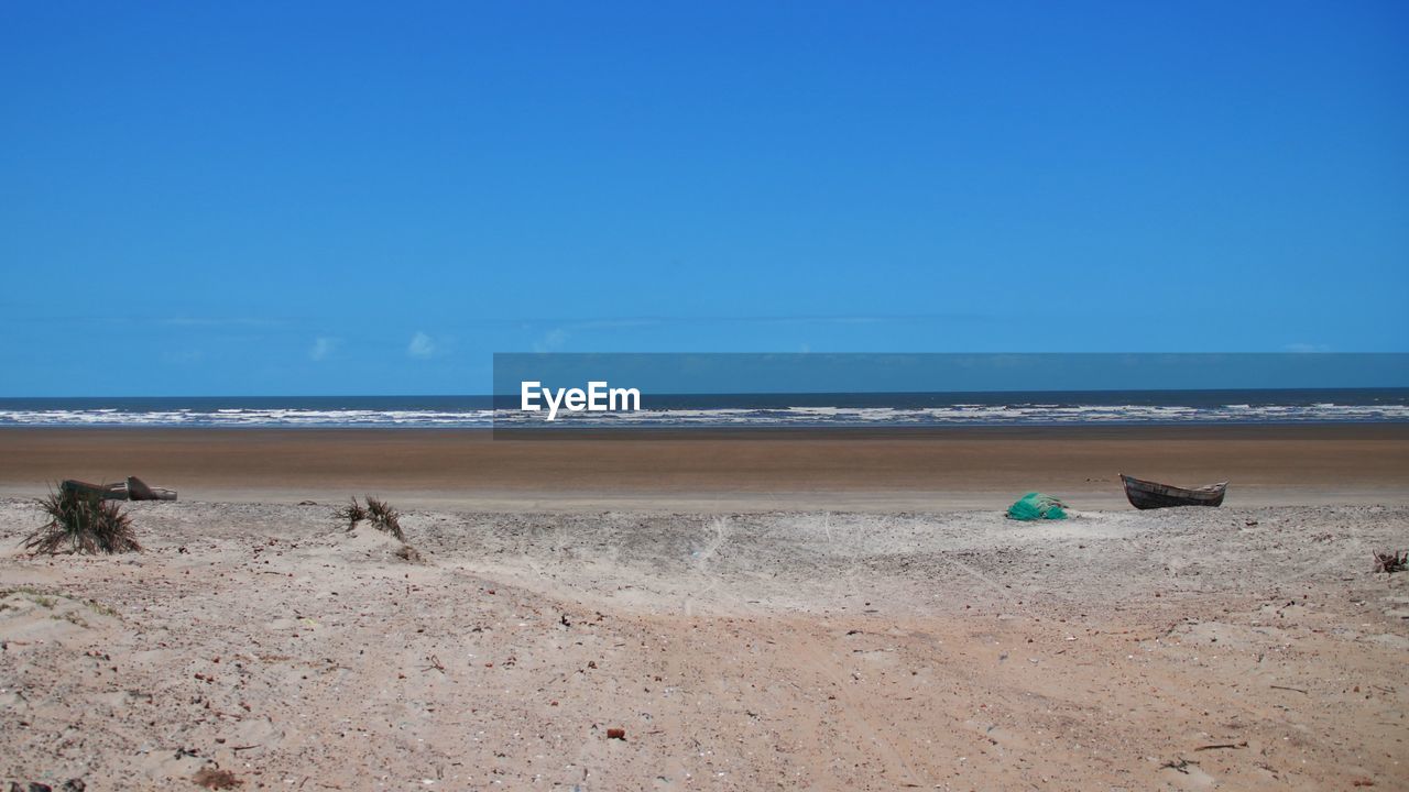 Scenic view of beach against clear blue sky