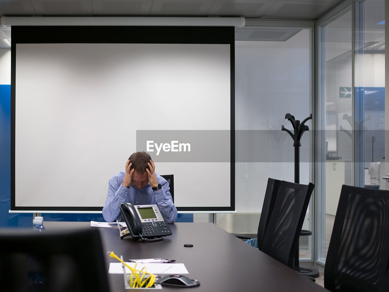 Frustrated businessman sitting against projection screen in board room at office