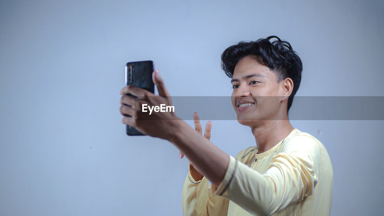PORTRAIT OF YOUNG MAN USING MOBILE PHONE