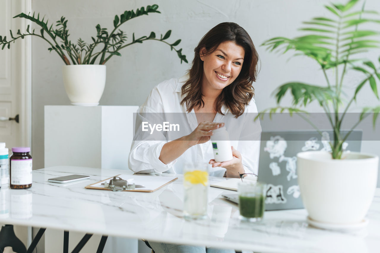 Young woman nutritionist in white shirt work at laptop. doctor communicates with the patient online