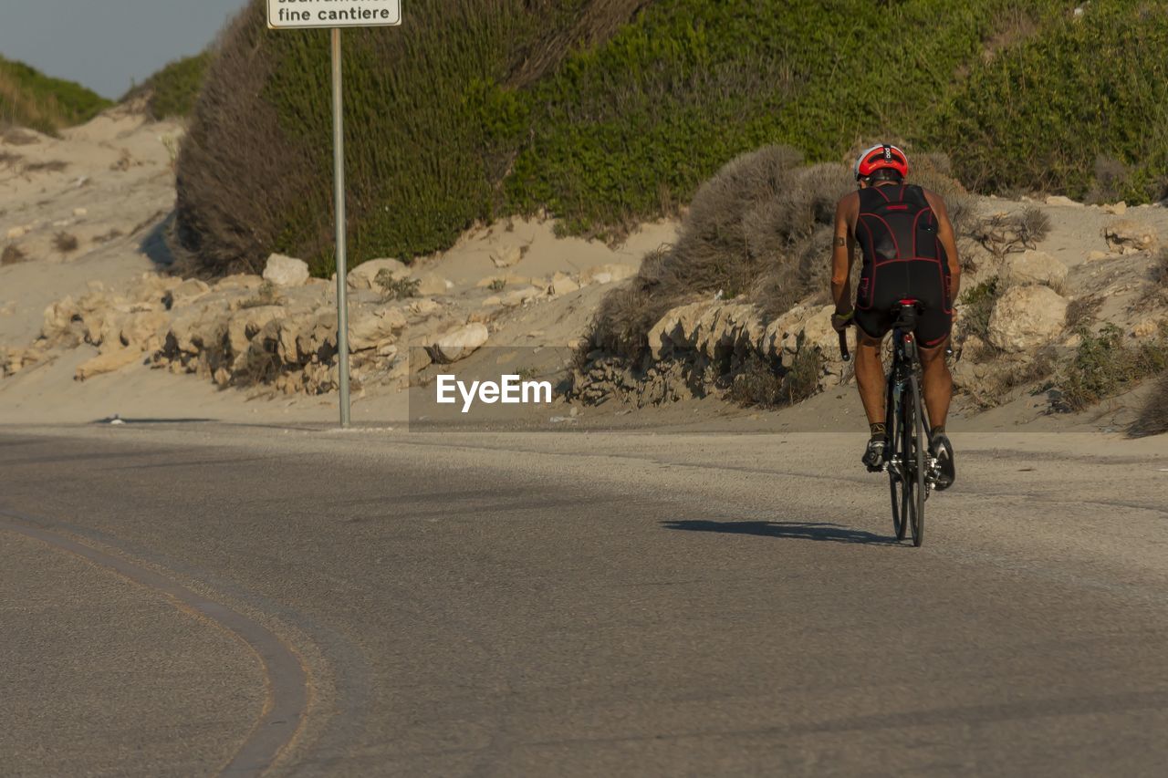 MAN RIDING BICYCLE ON ROAD