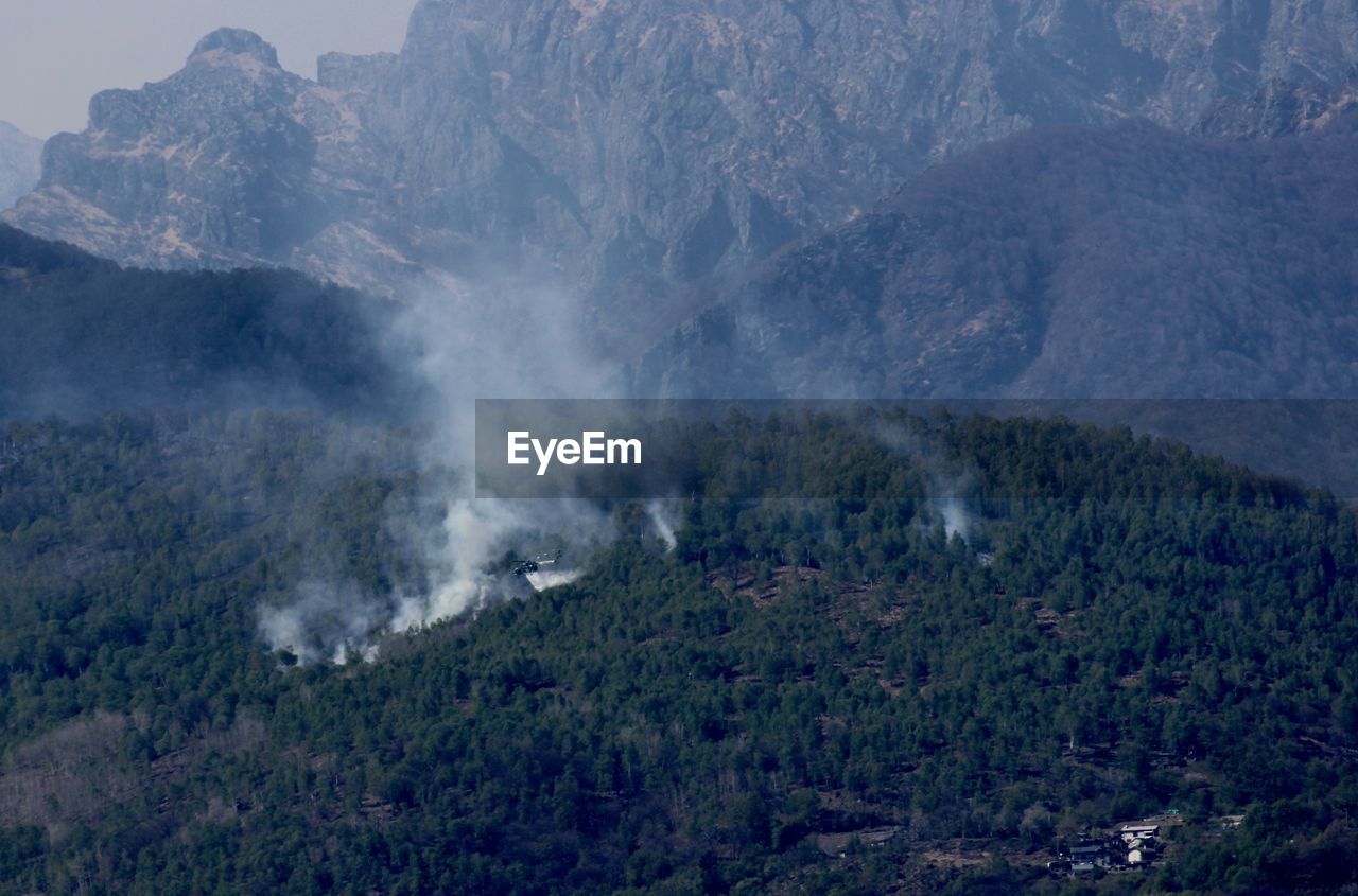 Aerial view of small village and hill on fire and smoke. a helicopter extinguish a fire 
