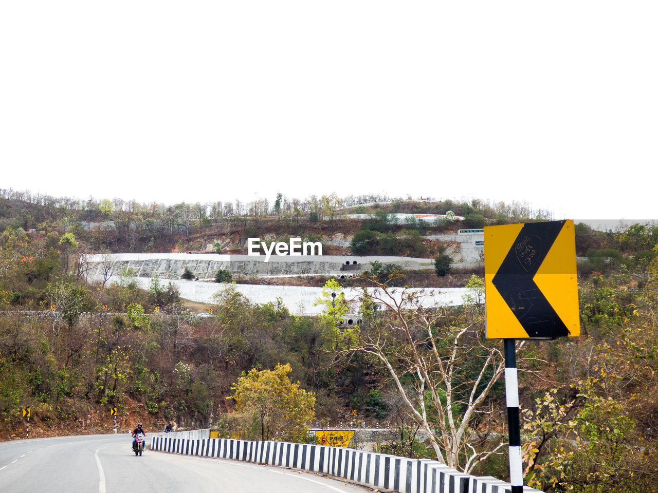 Man riding motorcycle on bridge against clear sky