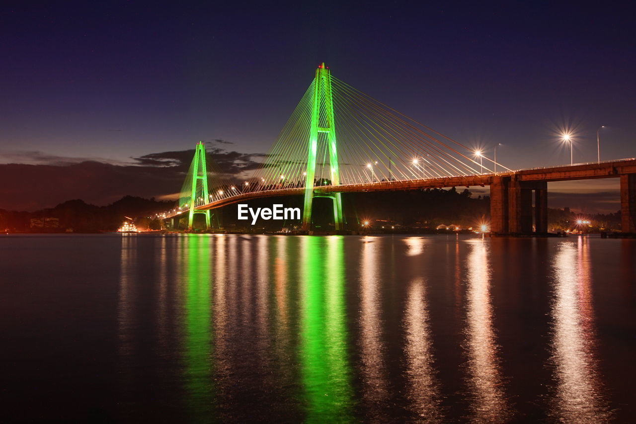 Illuminated bridge over river at night