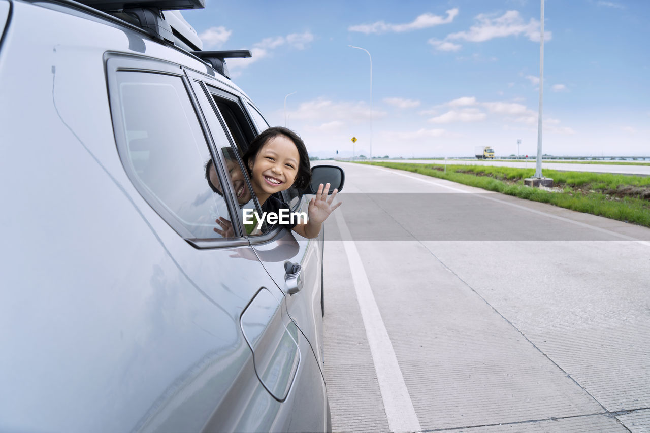 Portrait of girl waving from car