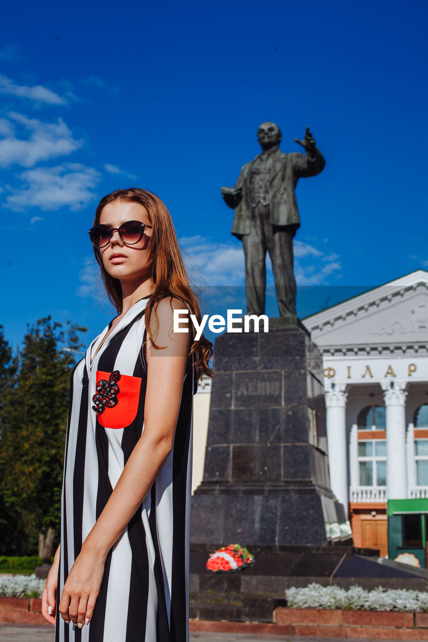 Fashionable young woman standing in city during sunny day