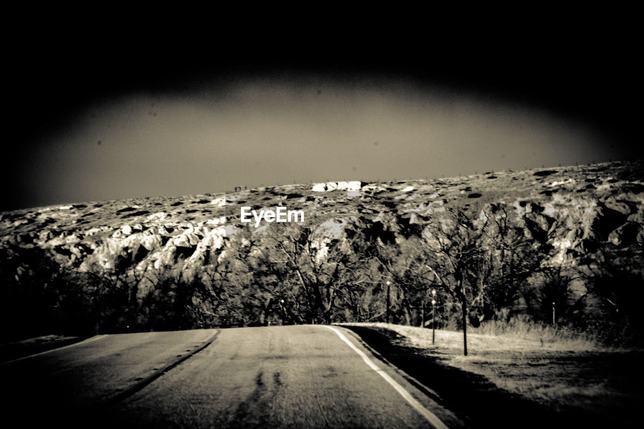 ROAD BY MOUNTAINS AGAINST SKY