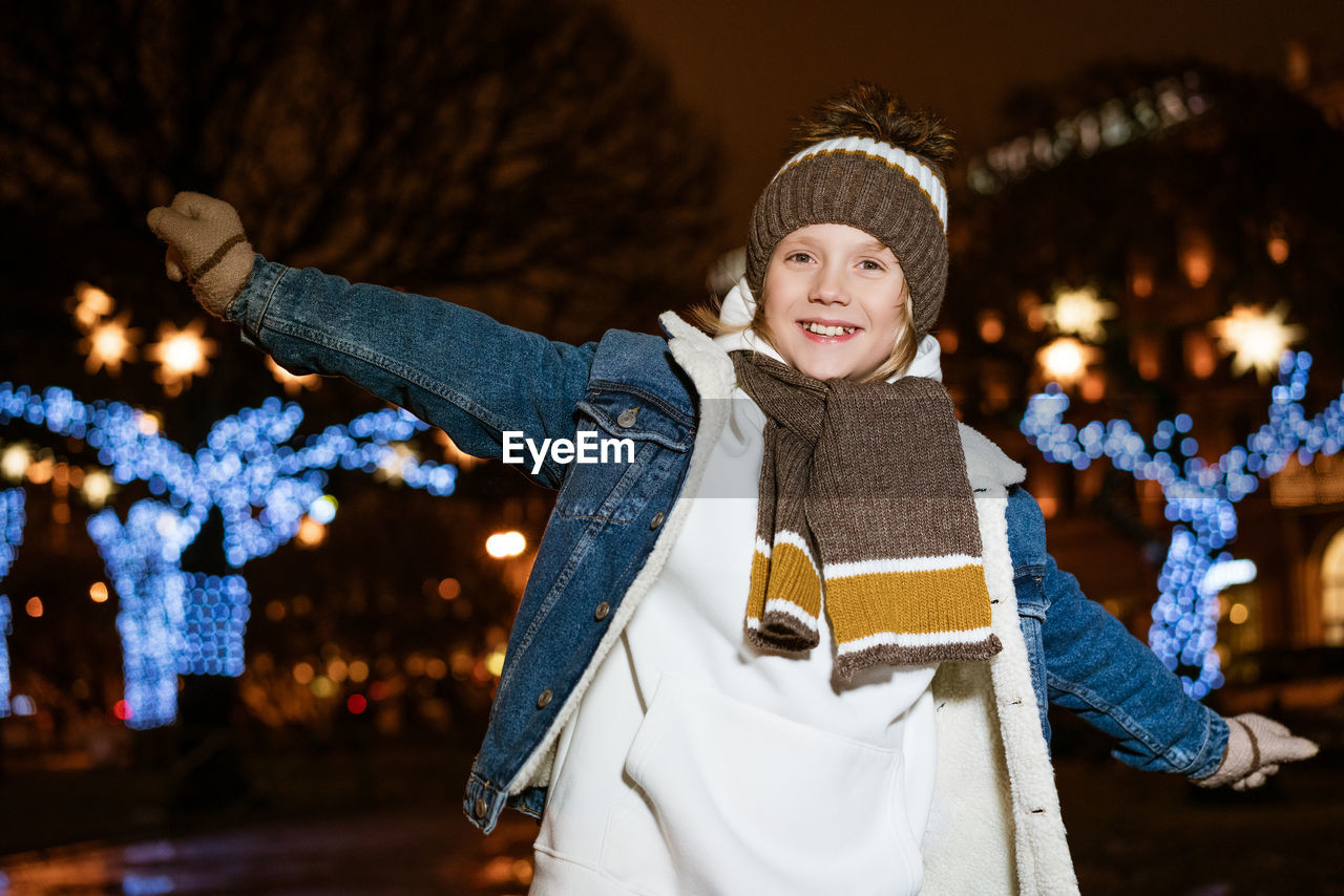 Portrait of joyful caucasian teenager boy standing on street in evening in city