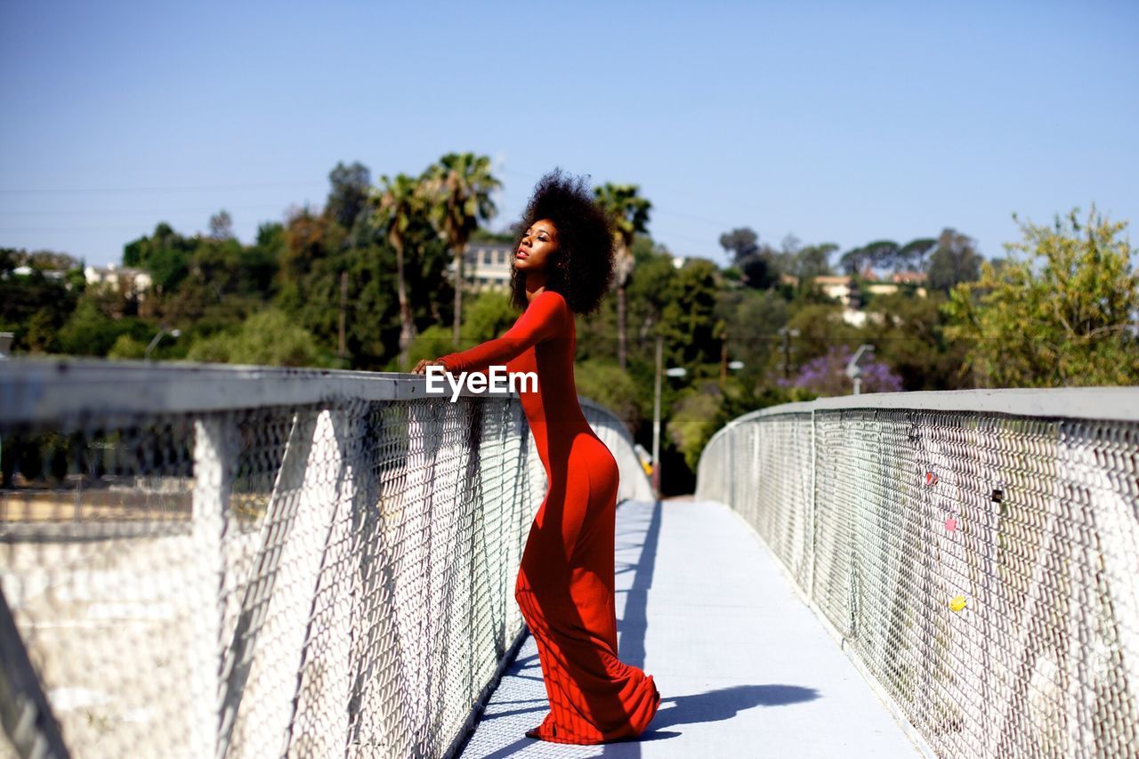 Side view of beautiful young woman standing on footbridge