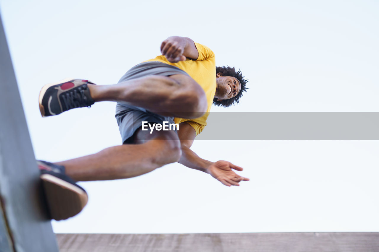 Low angle view of man exercising against sky