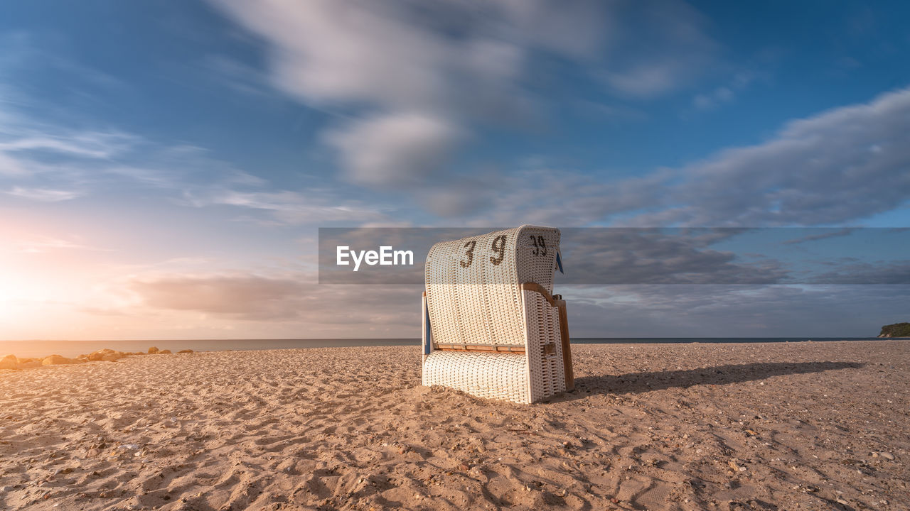 Hooded beach chair on sand against sky