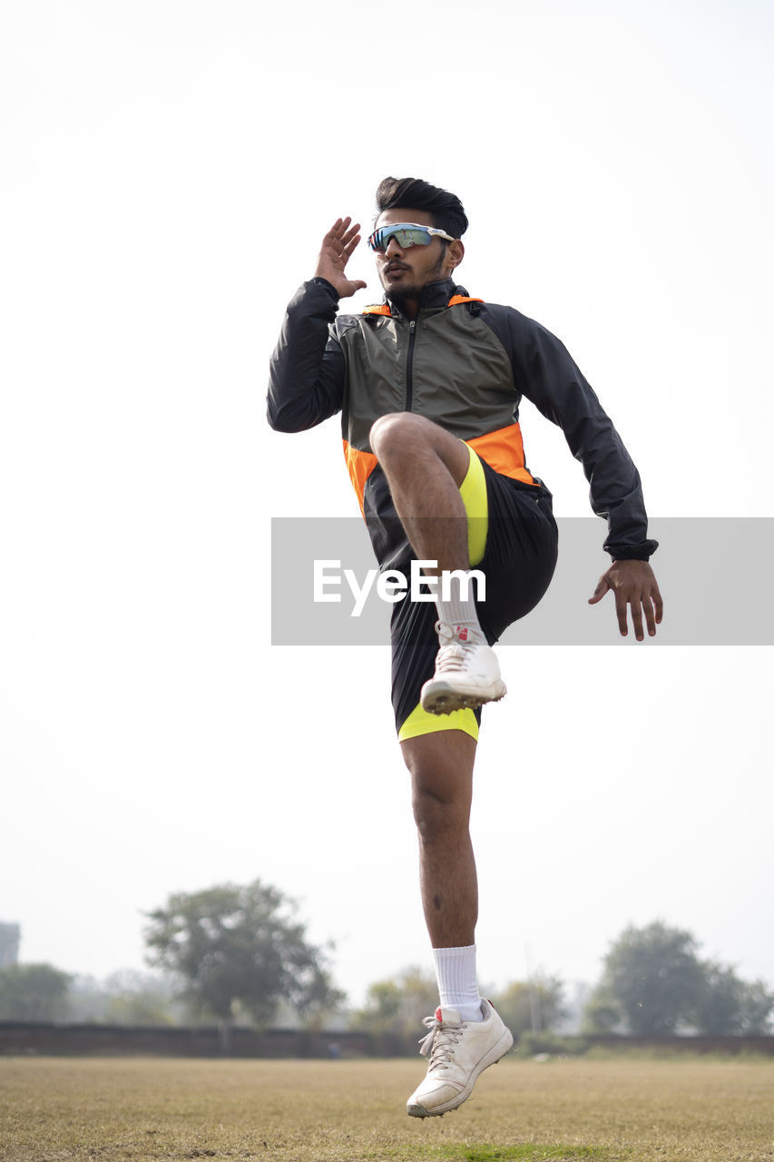 Young indian boy exercising and jumping on the sports field. sports and healthy lifestyle concept.