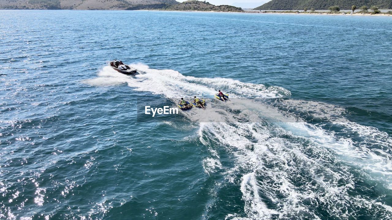 HIGH ANGLE VIEW OF PEOPLE IN BOAT AT SEA