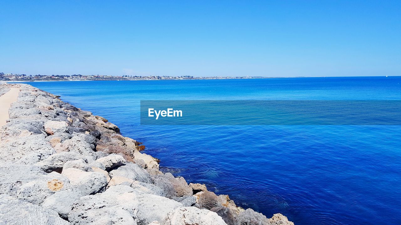 SCENIC VIEW OF SEA AND ROCKS AGAINST CLEAR BLUE SKY