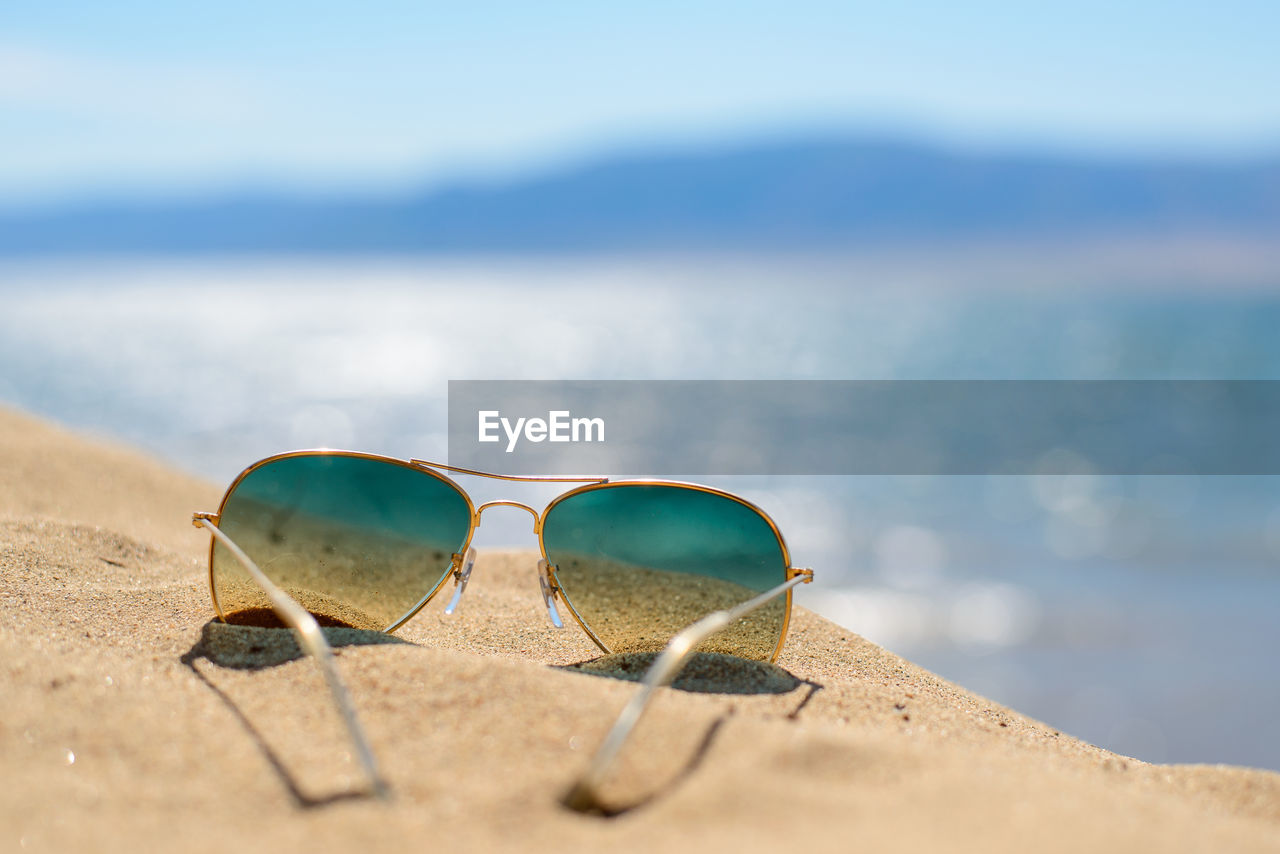 Close-up of sunglasses on sand at beach