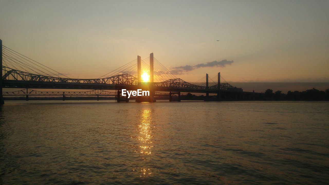 View of suspension bridge over river at sunset