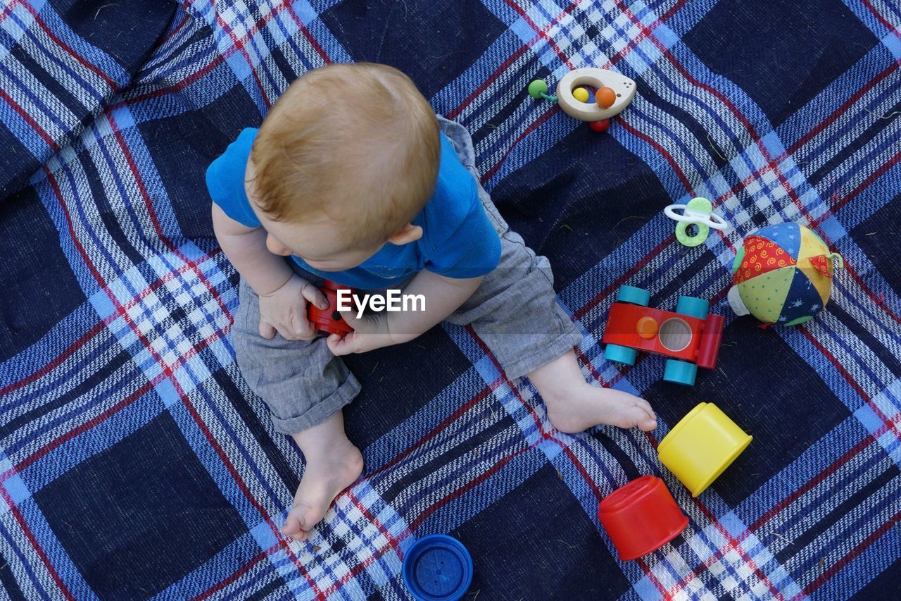 High angle view of baby boy playing with toys on blanket