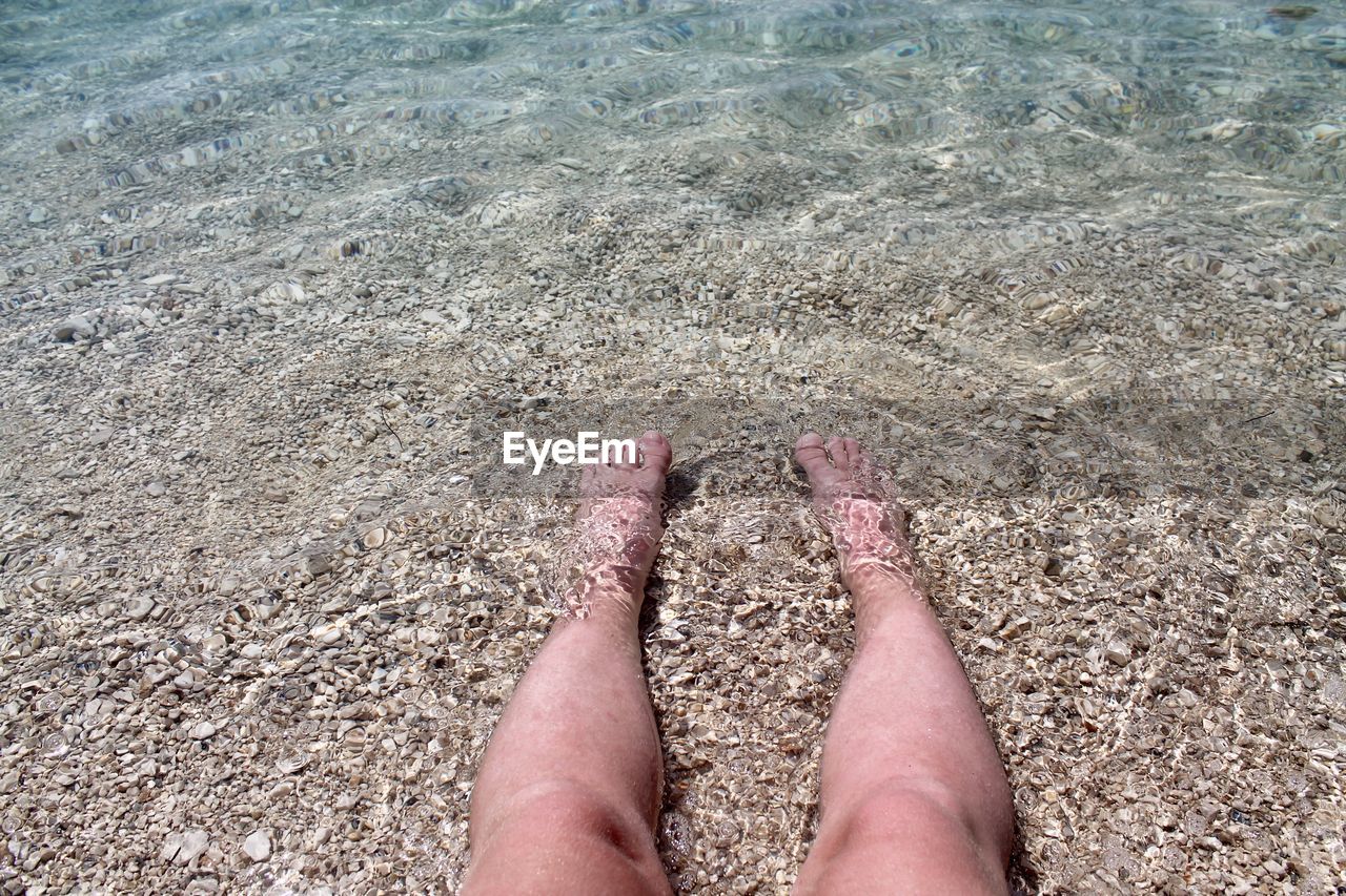 Low section of person legs on sand at beach