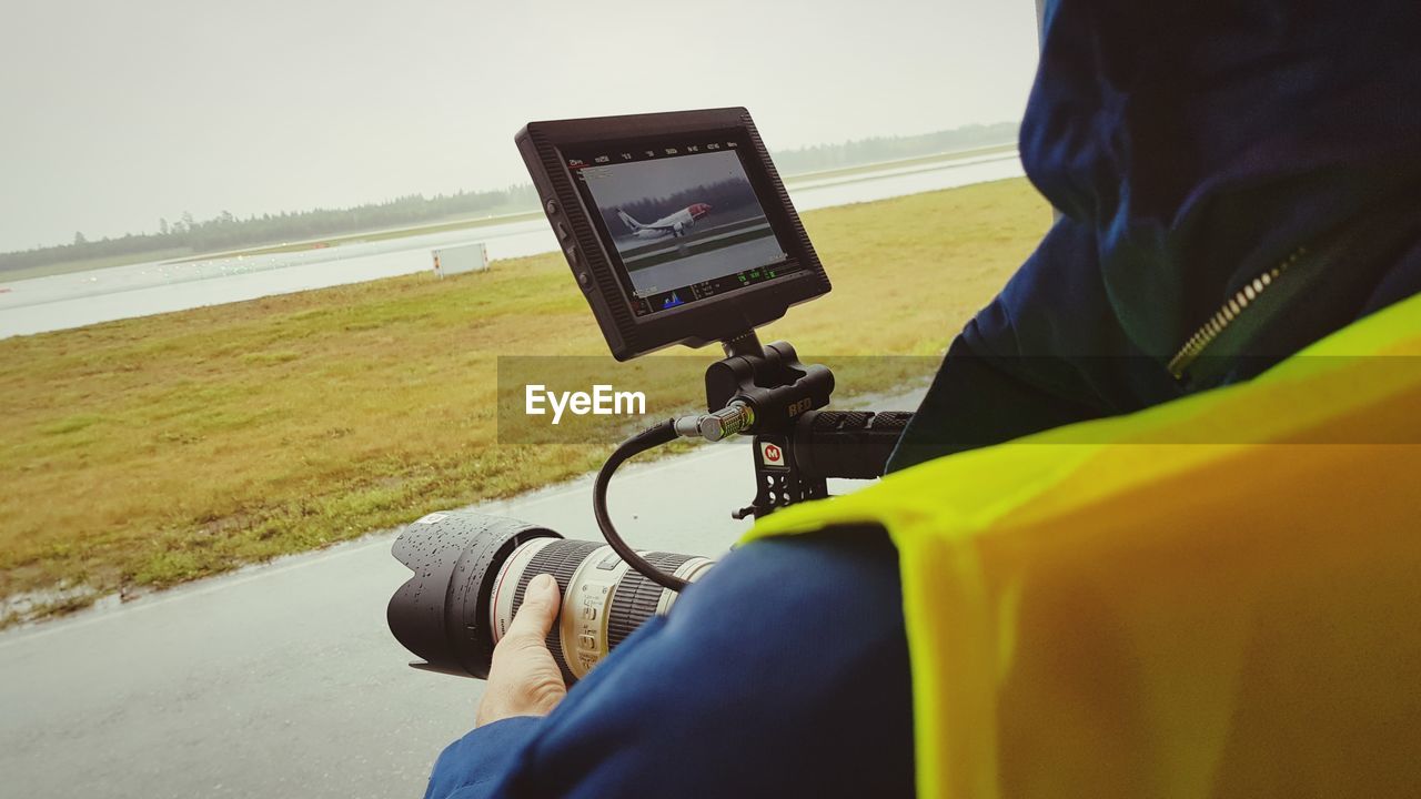 LOW SECTION OF MAN PHOTOGRAPHING WITH MOBILE PHONE ON ROAD