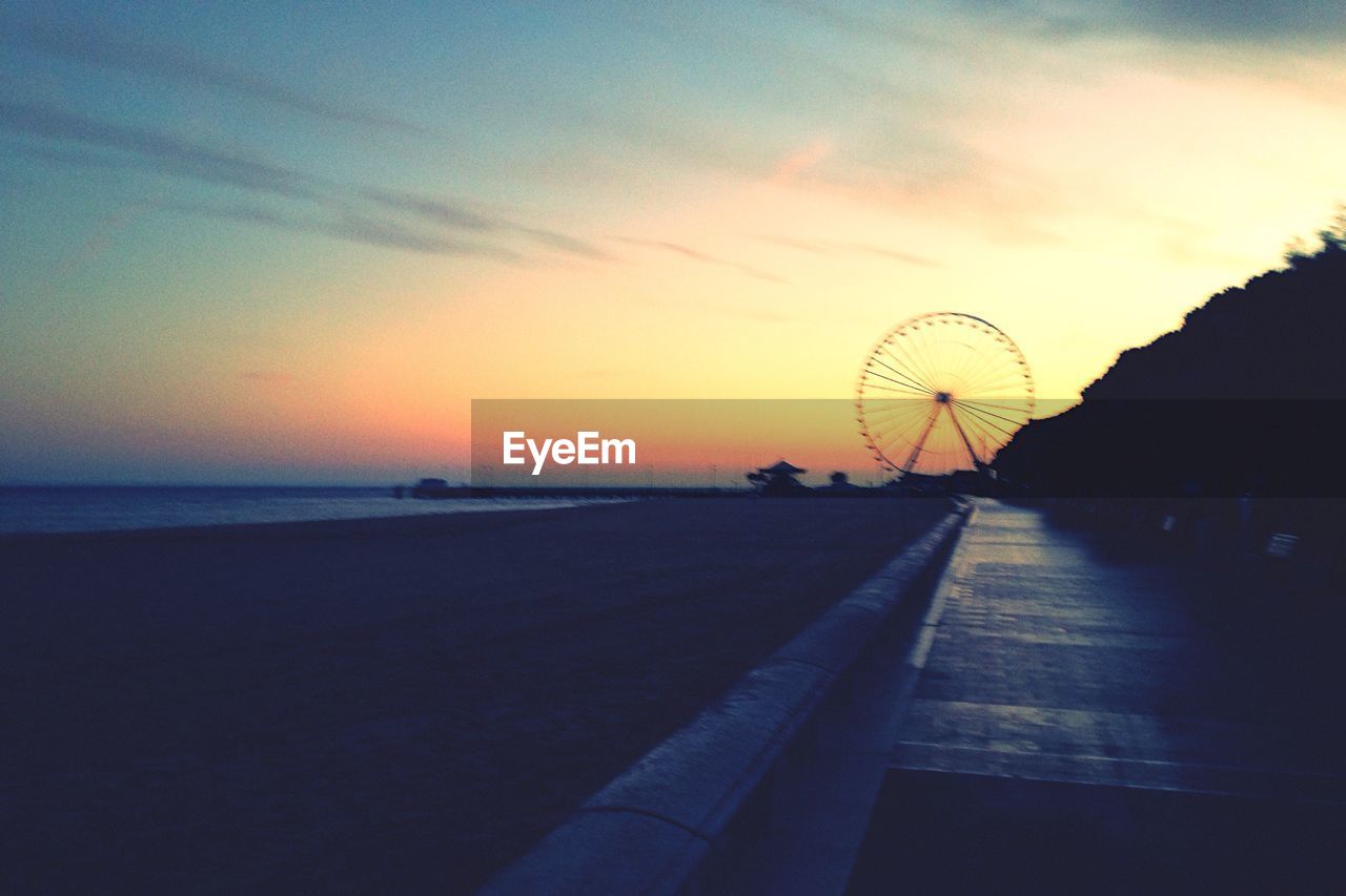 FERRIS WHEEL BY SEA AGAINST SKY