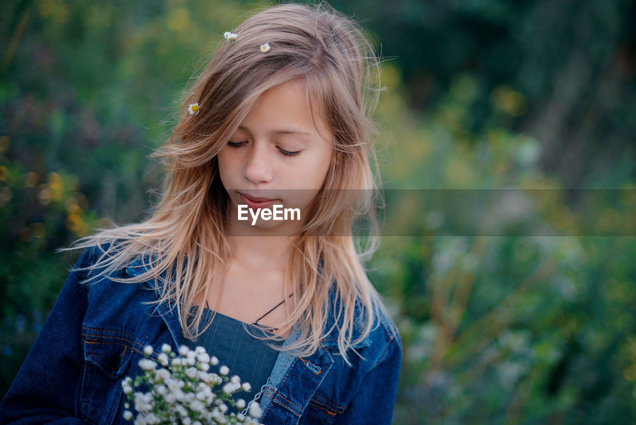 Portrait of young woman standing against plants