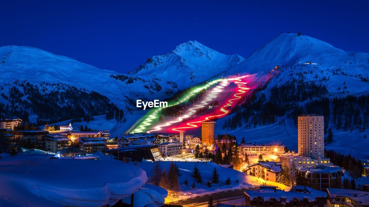 Aerial view of illuminated snowcapped mountains against blue sky at night