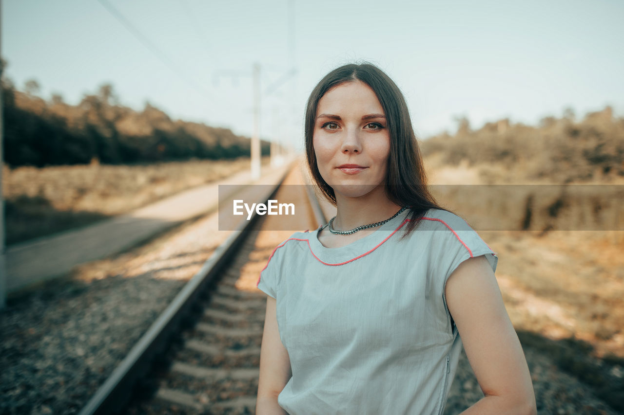 Portrait of young woman standing on railroad track