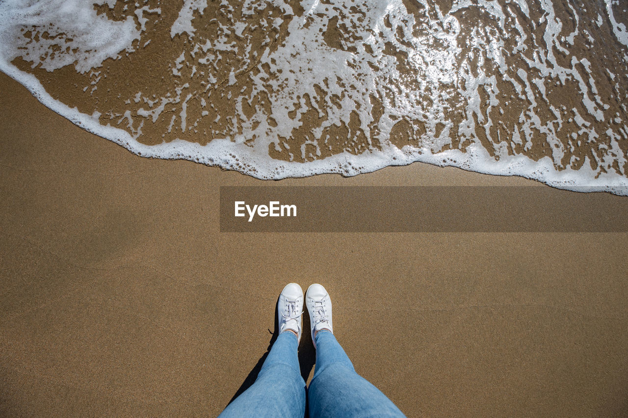 Low section of woman standing at beach