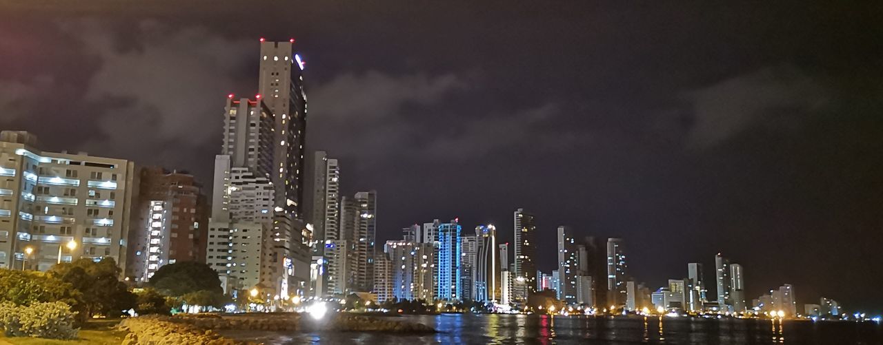 ILLUMINATED MODERN BUILDINGS IN CITY AGAINST SKY