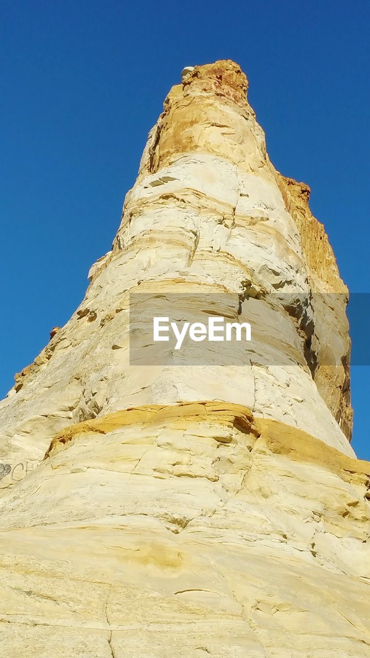 Low angle view of rock formation against clear blue sky