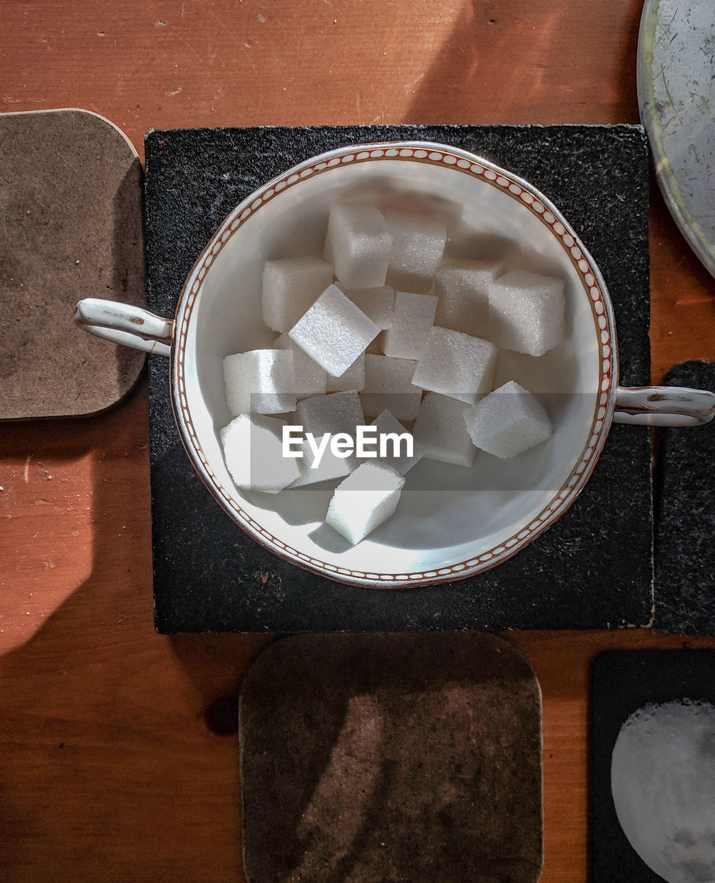 High angle view of sugar cubes in cup on sunlit table