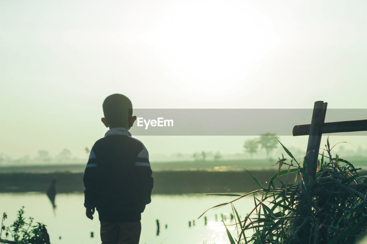 water, one person, nature, morning, lake, sky, men, silhouette, rear view, person, adult, tranquility, standing, beauty in nature, plant, reflection, outdoors, tranquil scene, copy space, lifestyles, fog, three quarter length, back lit, day, solitude