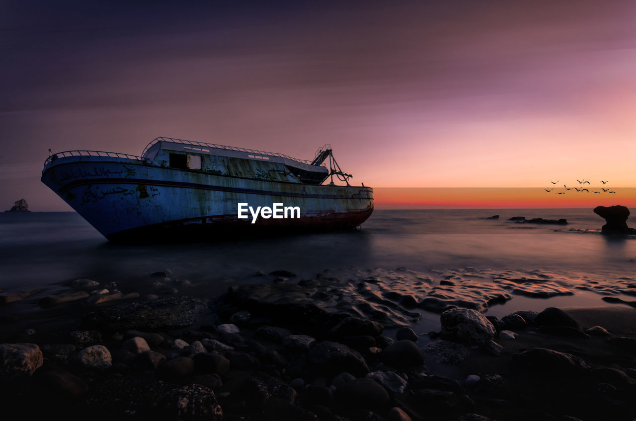 Scenic view of old boat at sea during sunset