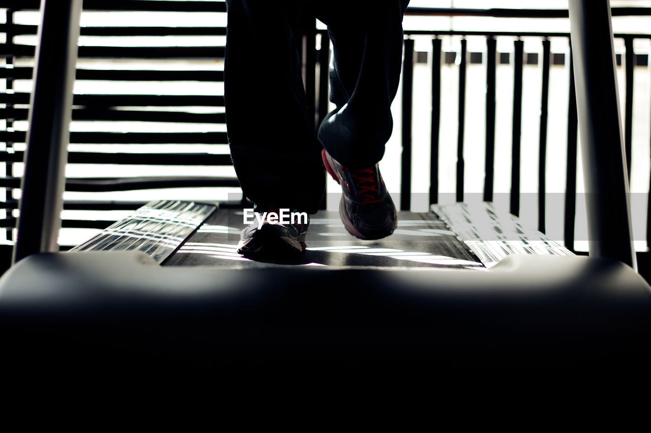 Low section of man running on treadmill at gym