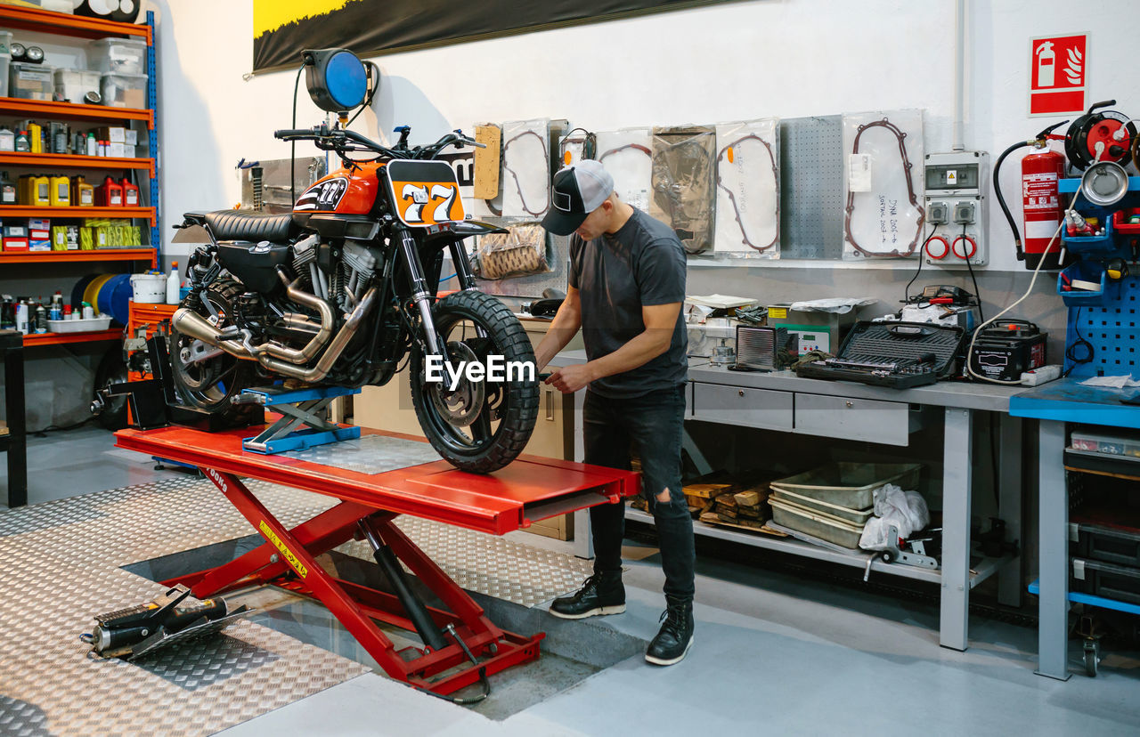 Mechanic man checking custom motorcycle over platform