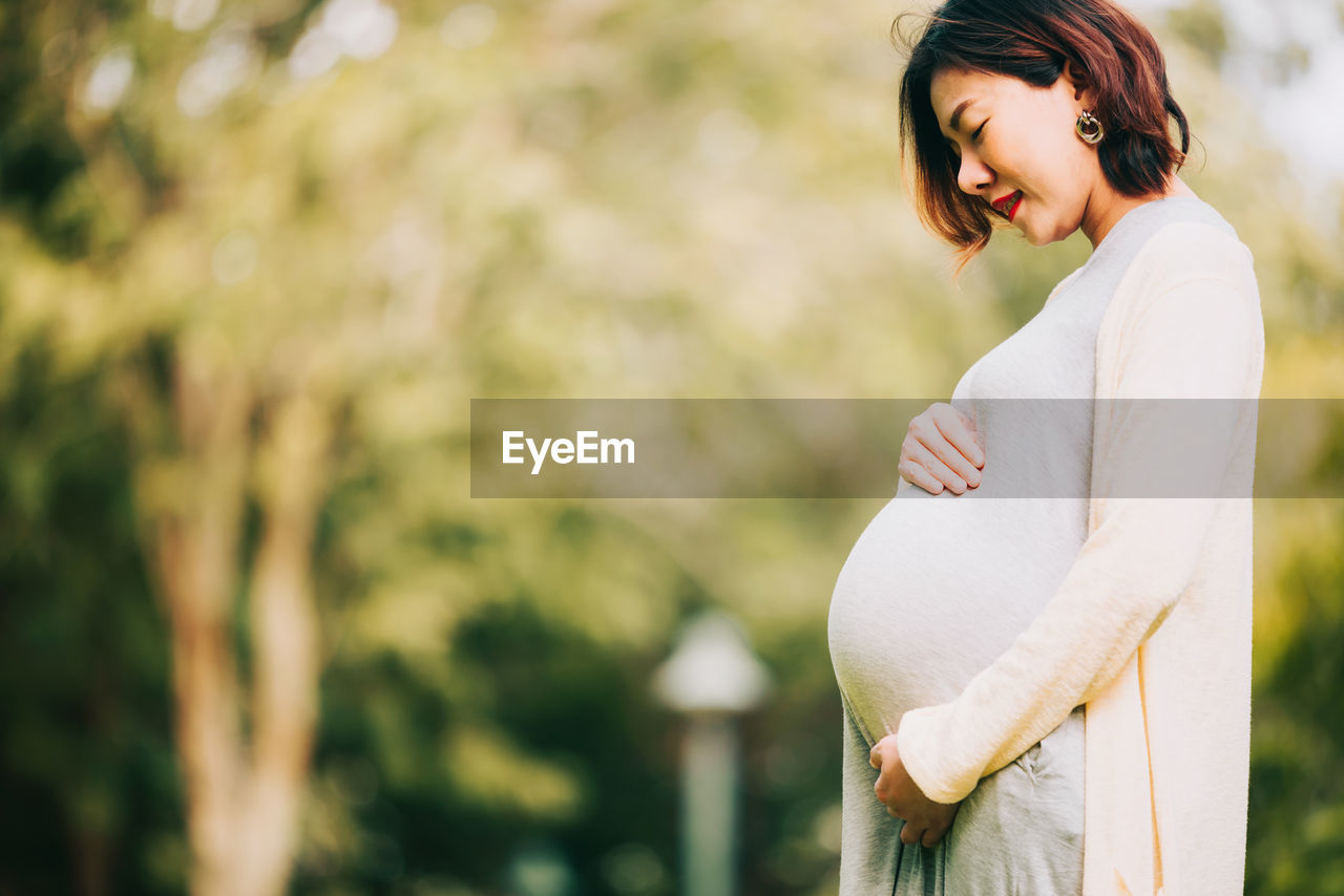 Side view of pregnant woman standing outdoors