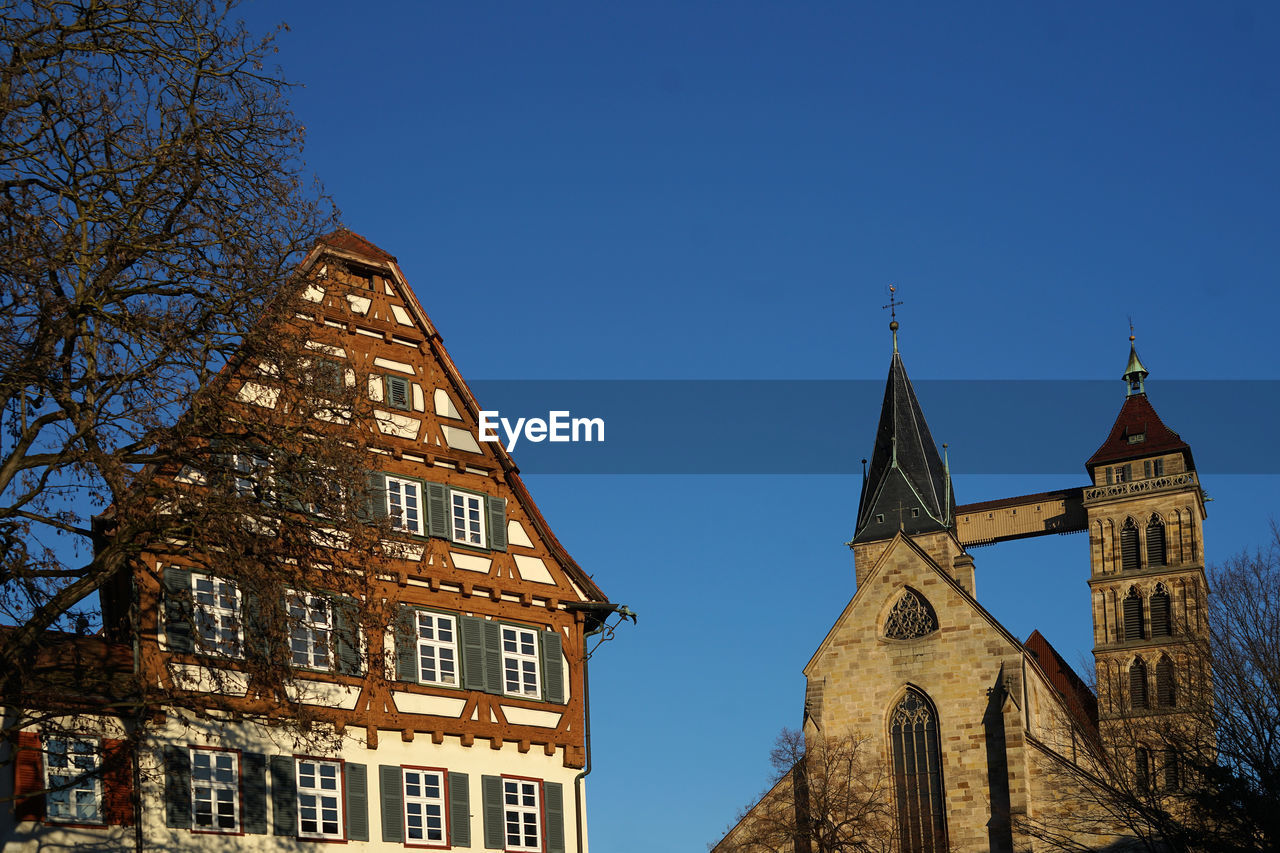 Im hintergrund die stadtkirche st. dionys in esslingen. davor ein historisches fachwerkhaus