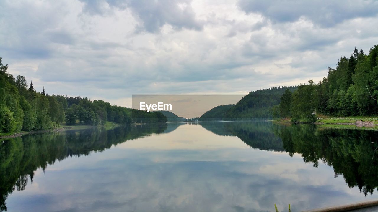 Scenic view of calm lake against cloudy sky