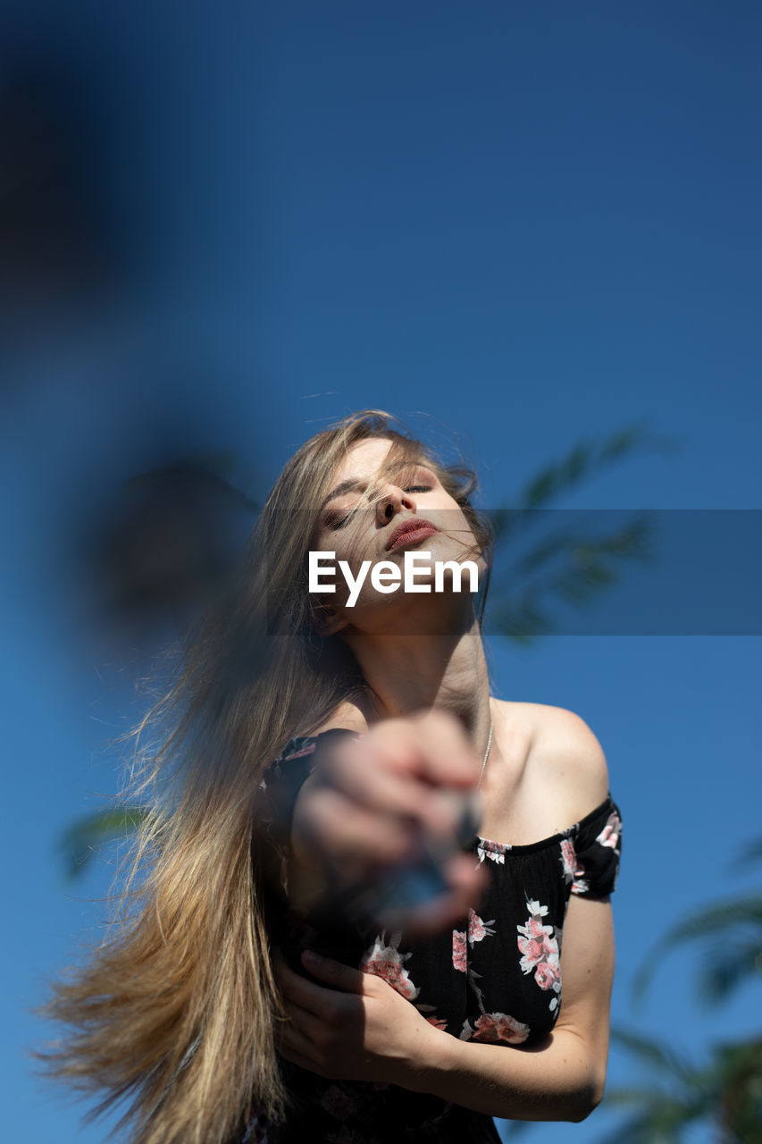 Portrait of woman standing against sky