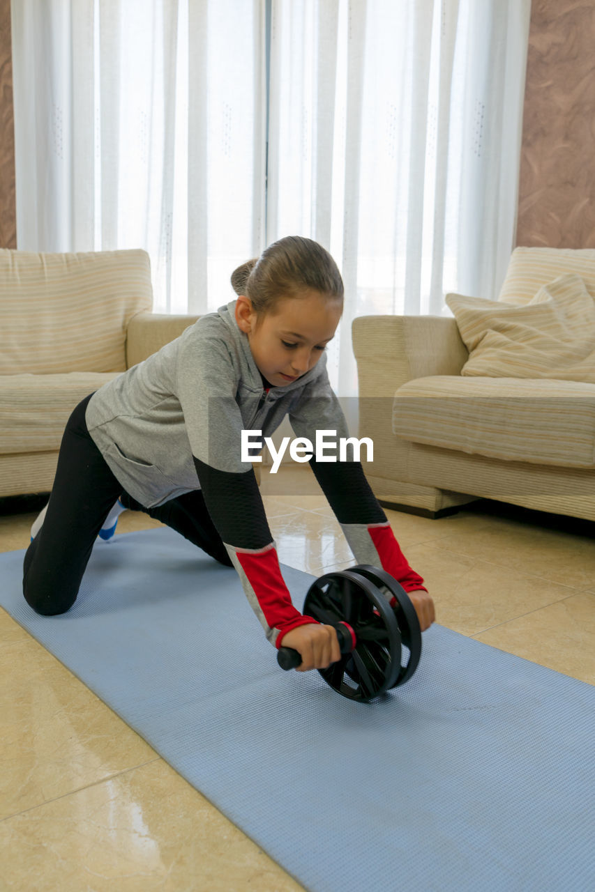 Full length of girl exercising at home