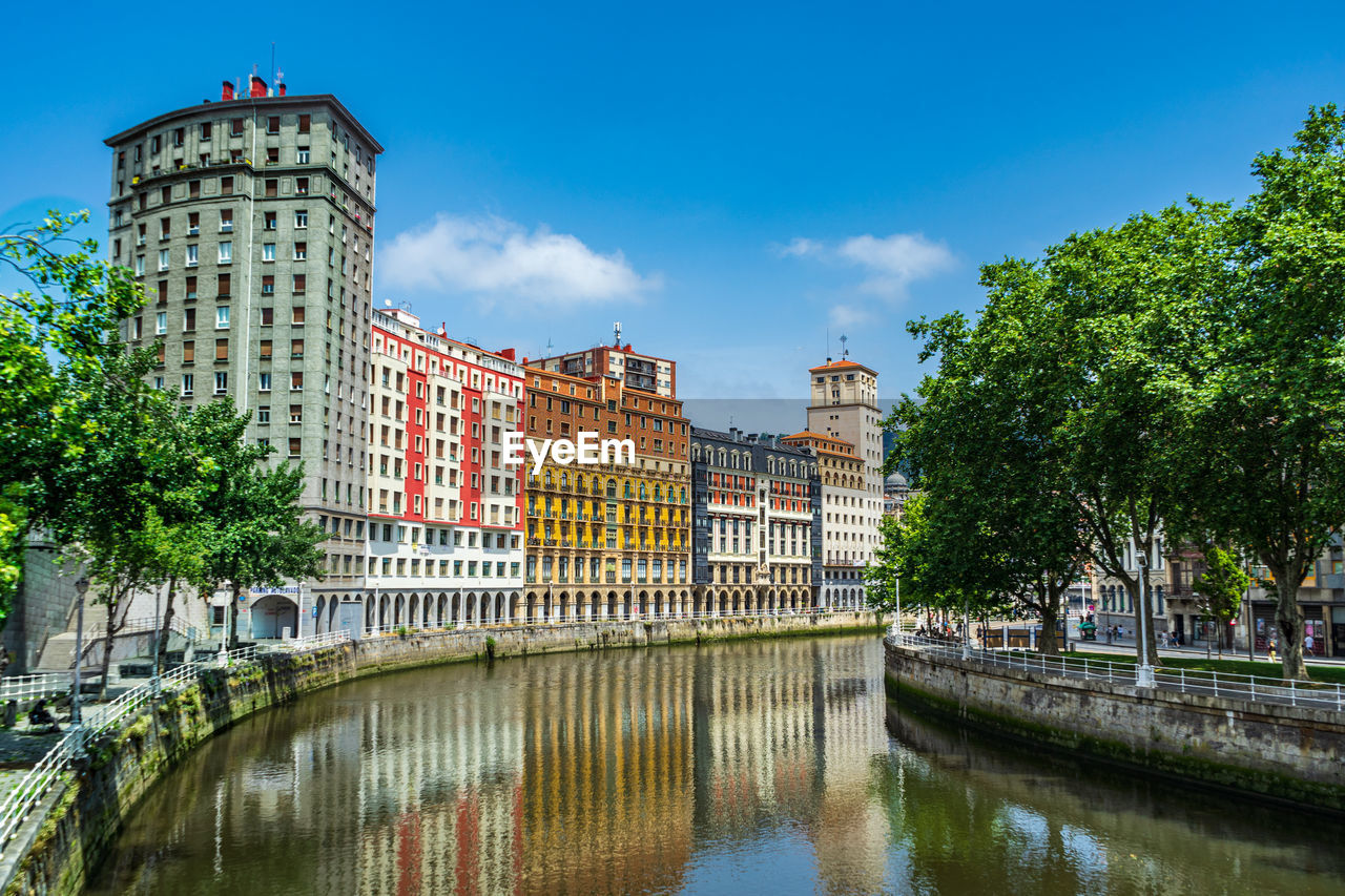 buildings by river against clear sky