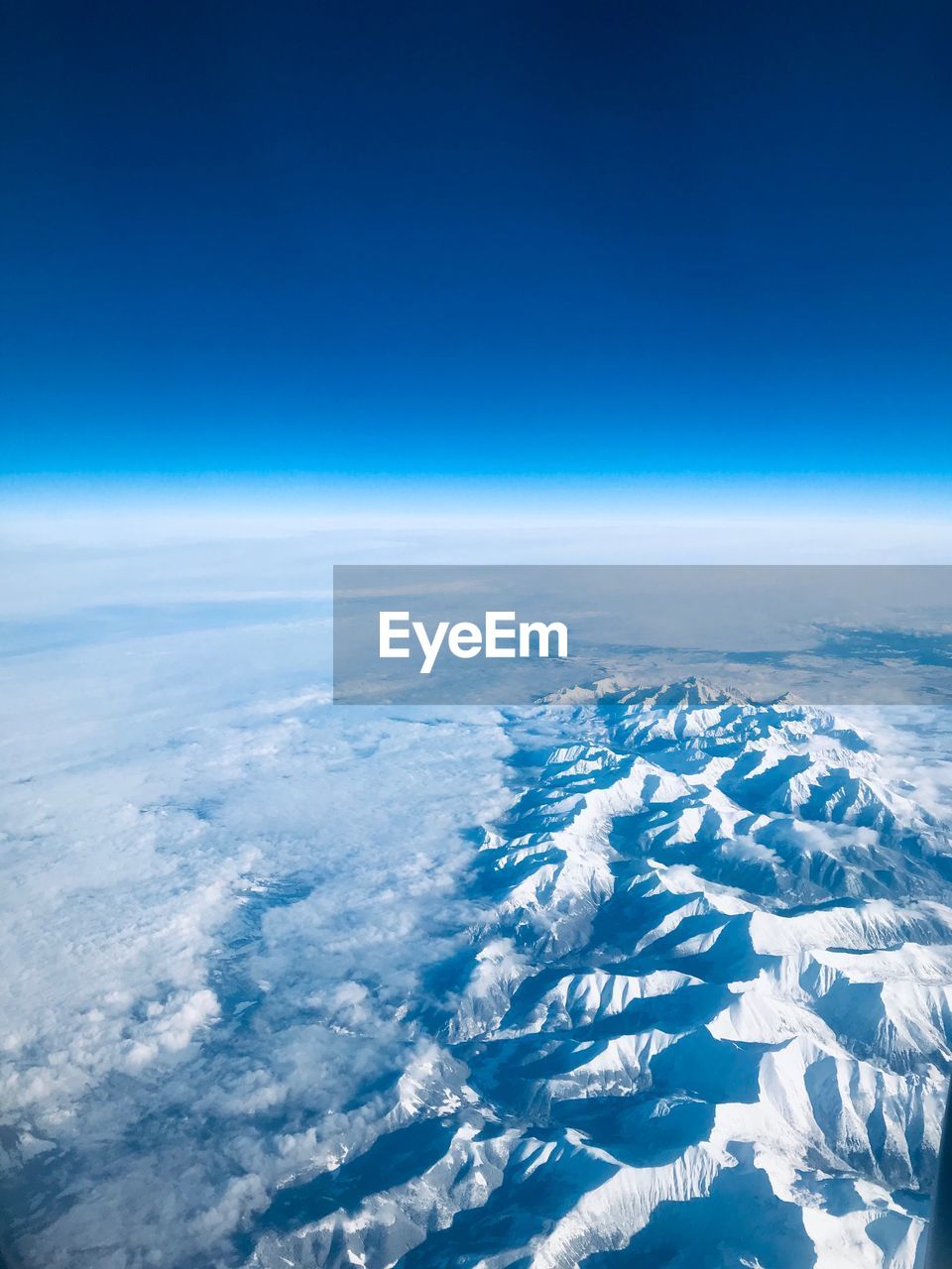 Aerial view of snowcapped landscape against blue sky