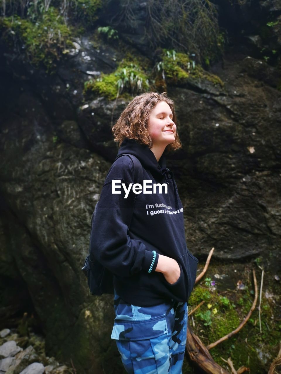 SMILING YOUNG WOMAN LOOKING AT FOREST