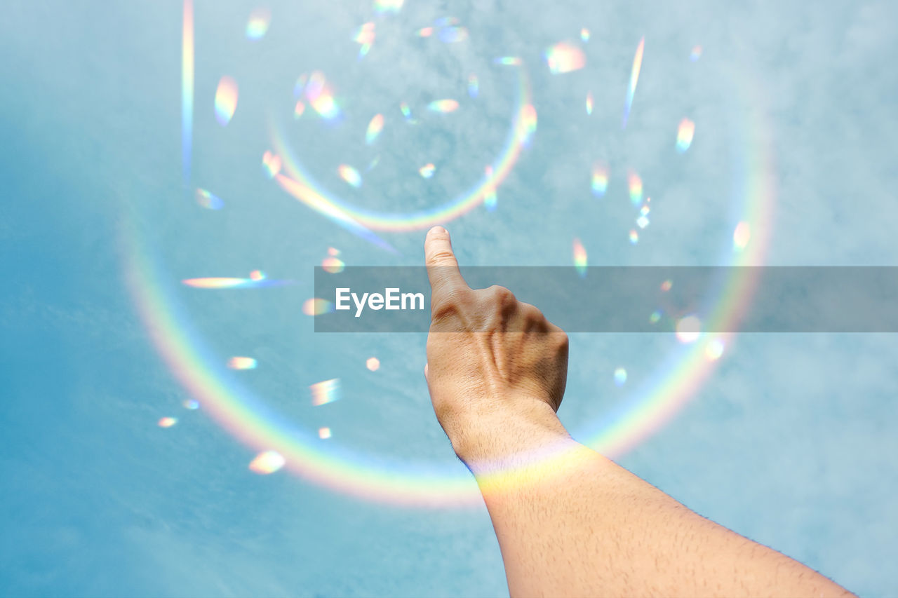 cropped hand of woman holding water against sky