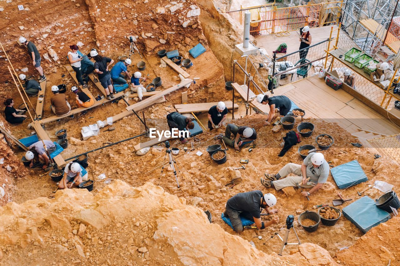 HIGH ANGLE VIEW OF PEOPLE WORKING AT CONSTRUCTION SITE AT SHORE