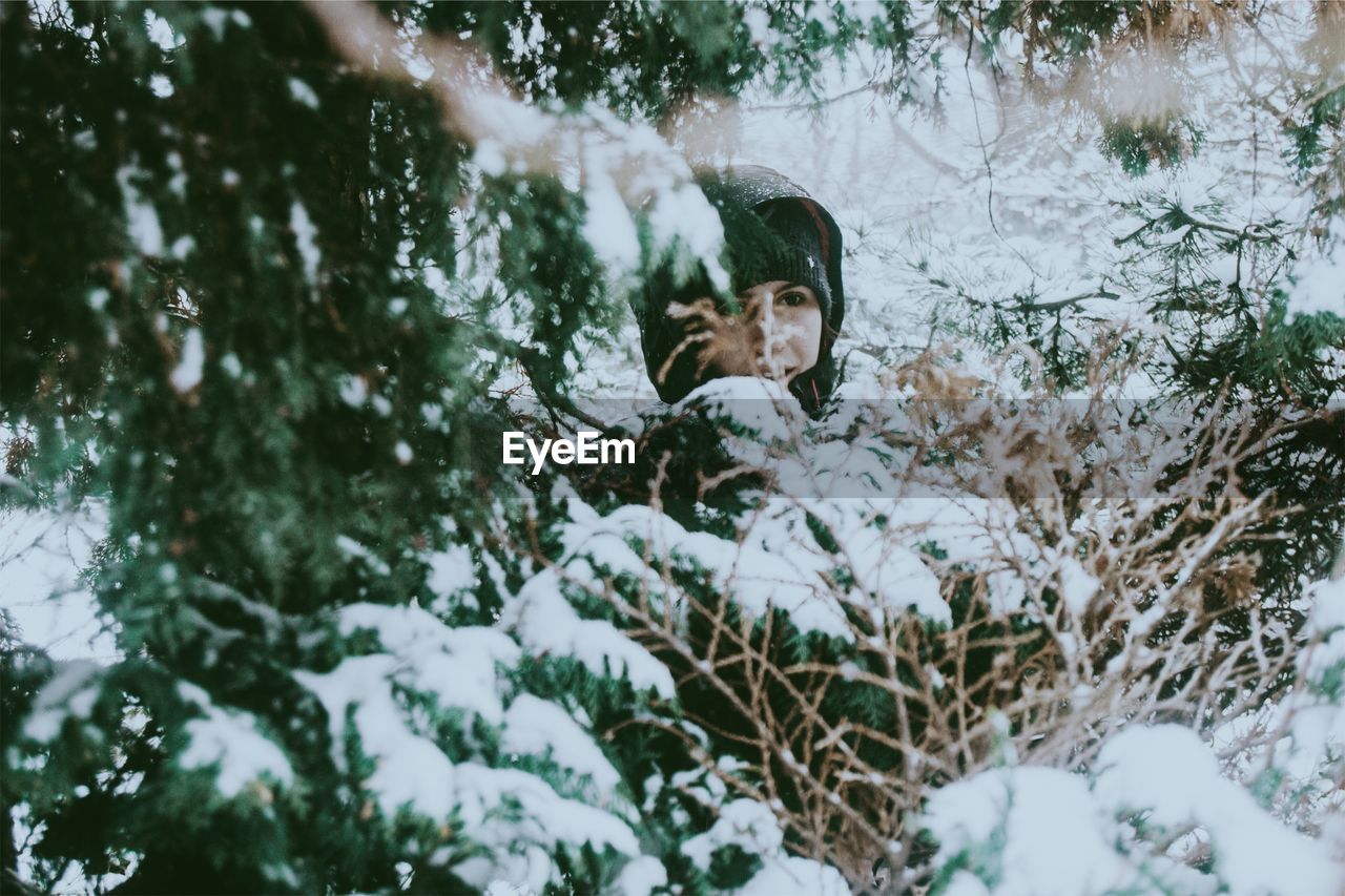 Woman amidst snow covered tree in forest