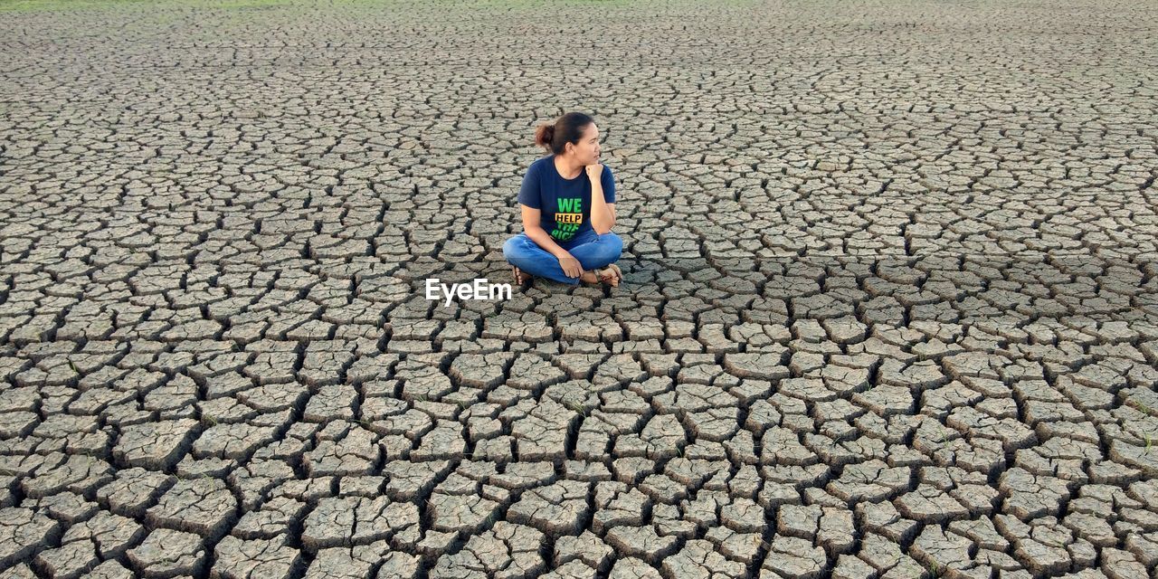 Full length of woman sitting on barren landscape