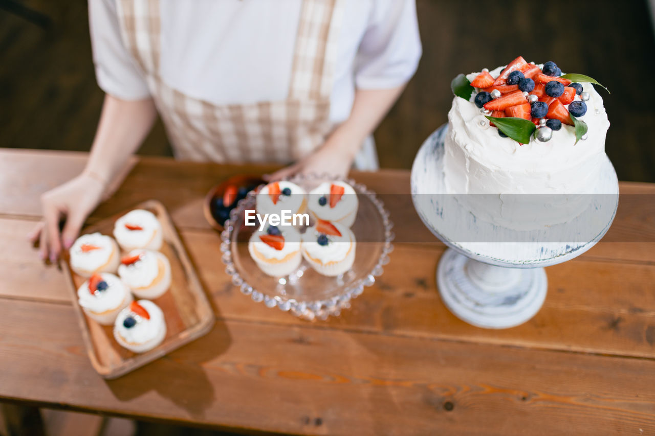 midsection of woman holding cake on table